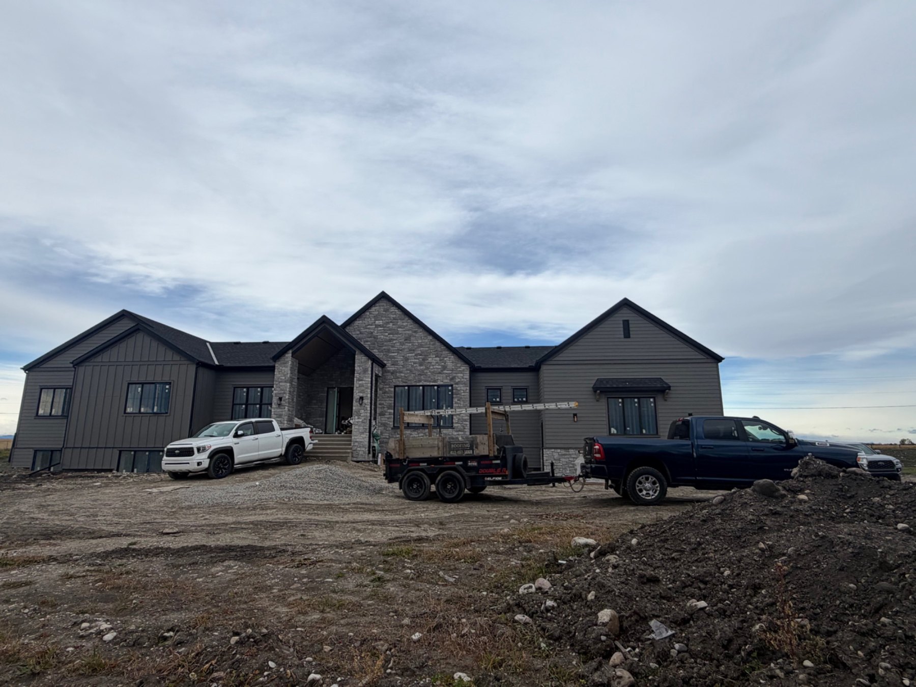 Completed new home exterior with grey siding and a dark roof